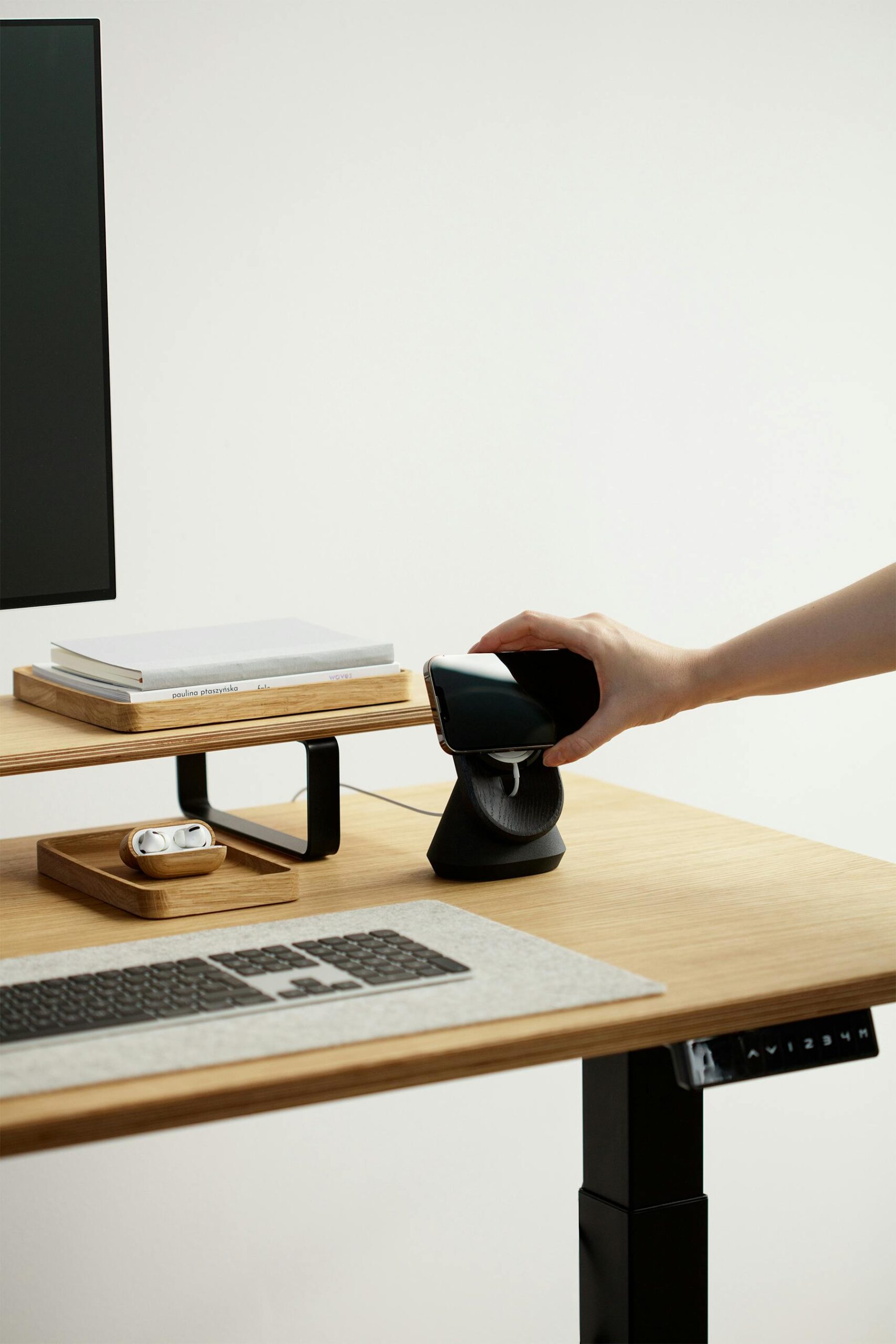 Minimalist workspace featuring a wireless charging station on an adjustable desk.