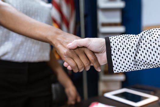 Close-up of two professionals shaking hands in a business environment.